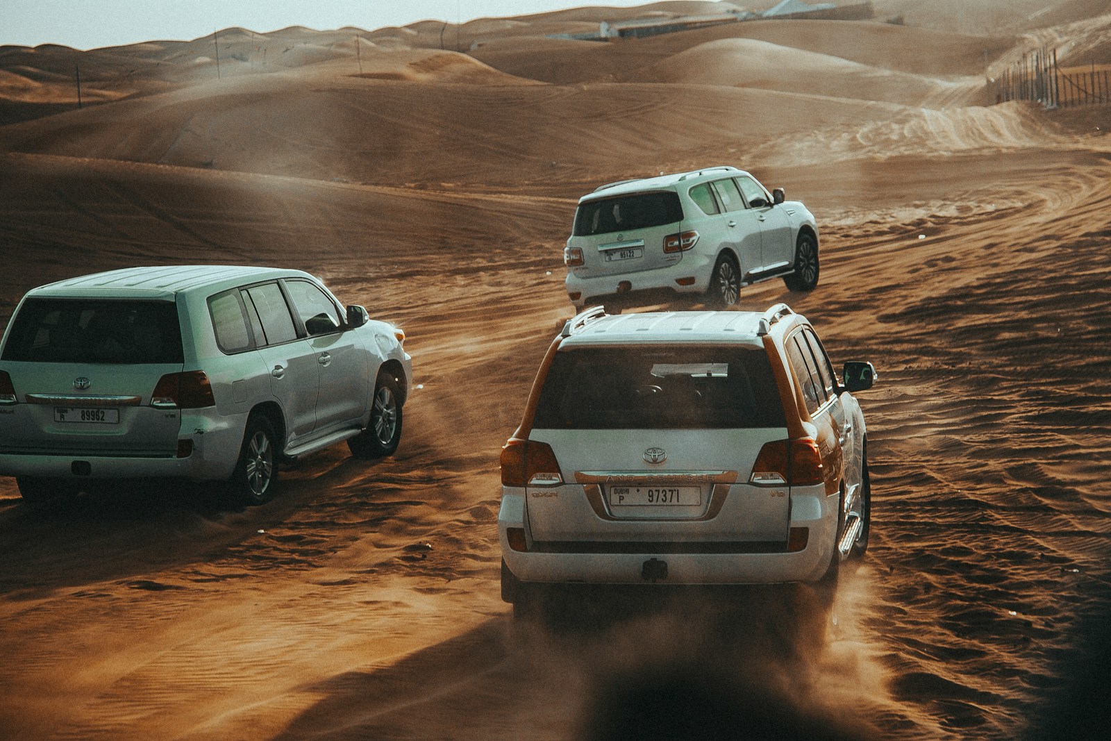 a group of cars driving on a dirt road