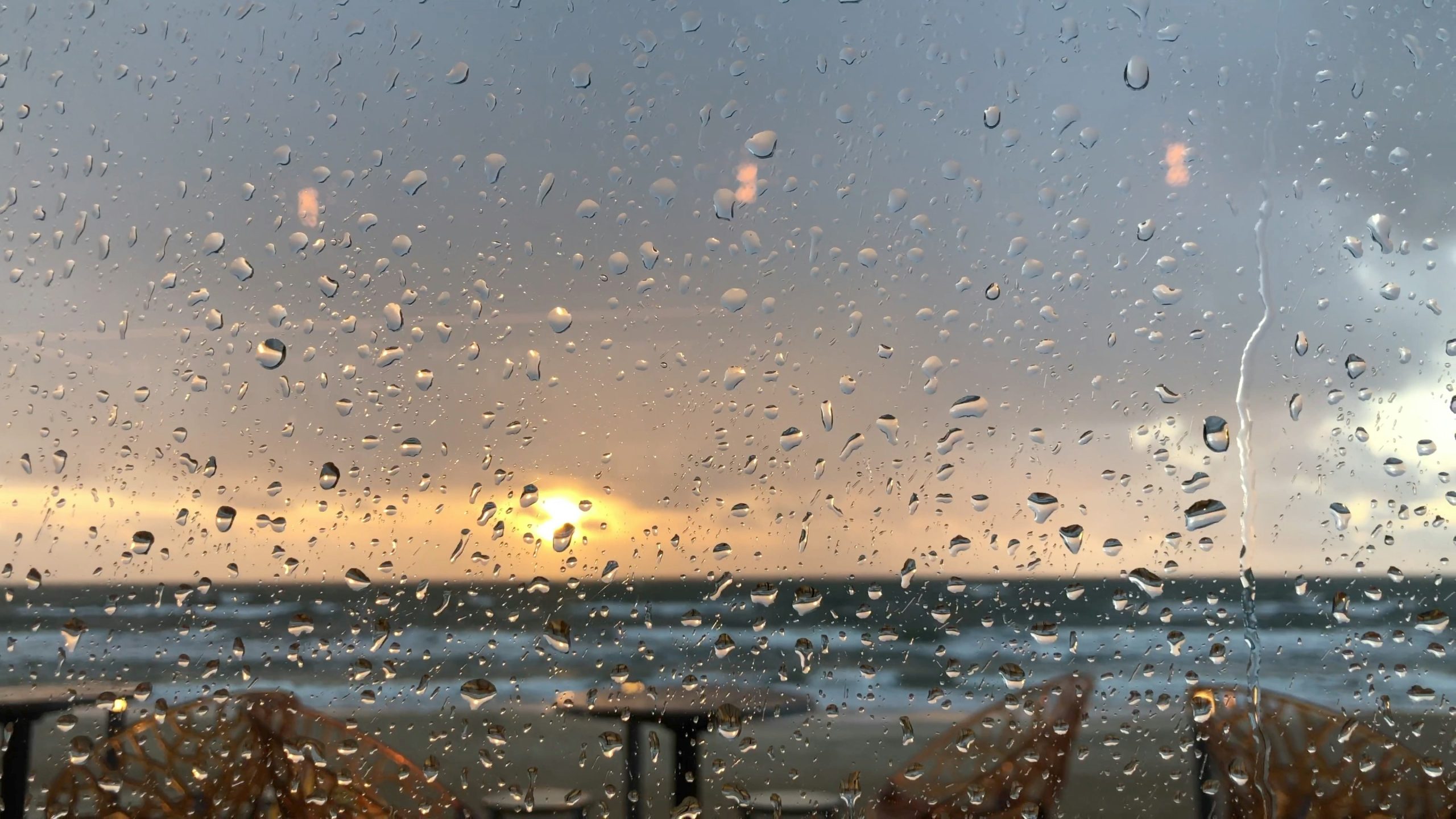 a view of the ocean through a rainy window