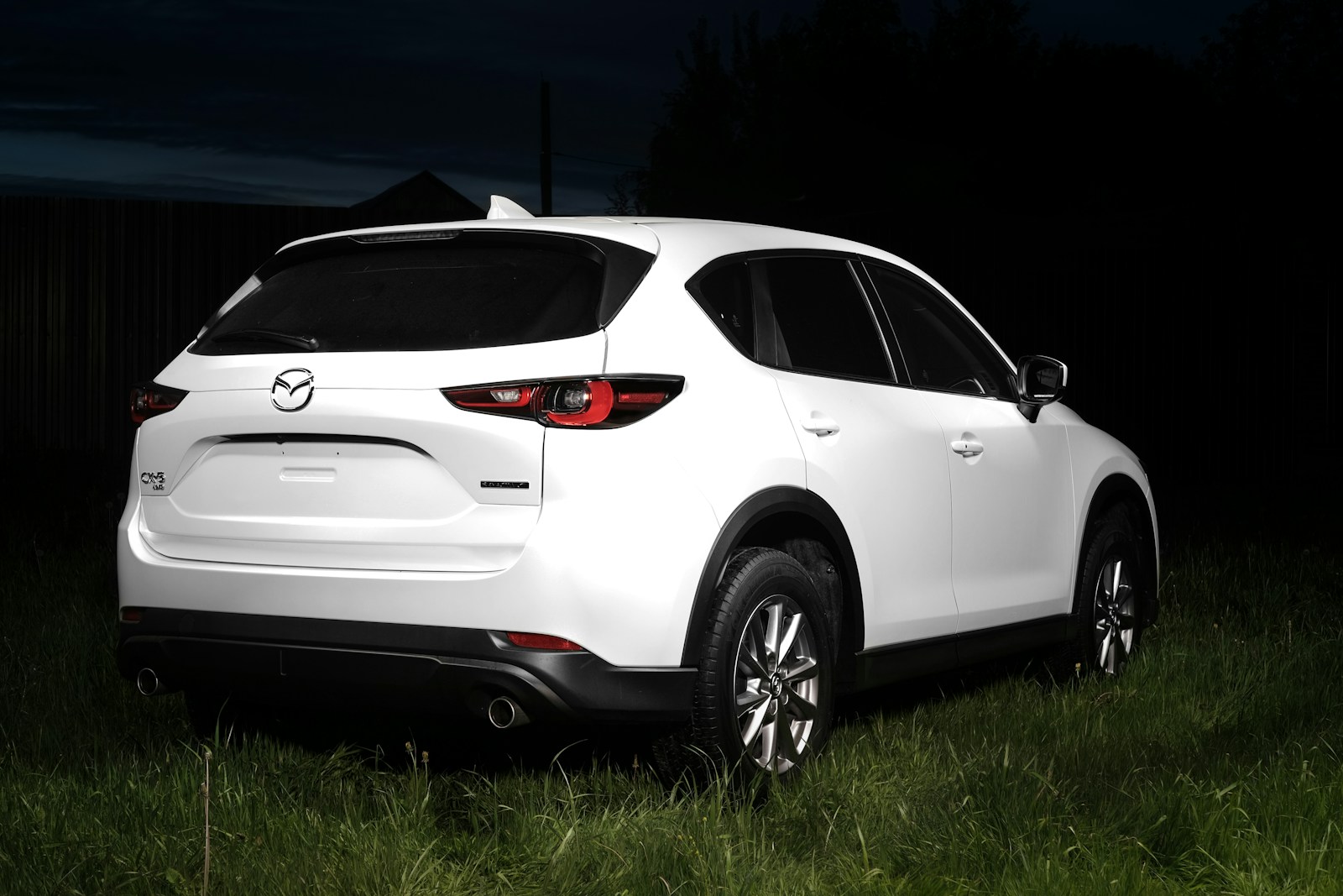a white mazda cx - 5 parked in a field at night