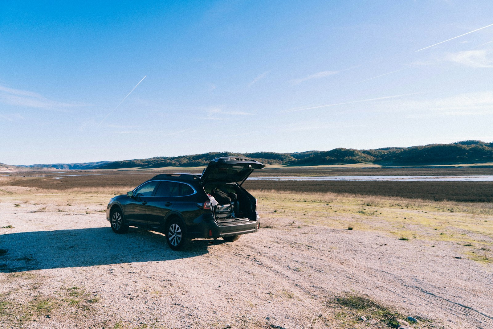 a car with its trunk open on a dirt road